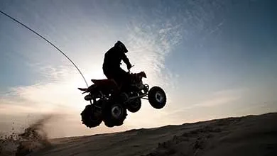 Description Silhouette of a person jumping quadbike in the Oregon dunes