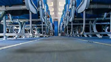 Low-angle view down an airplane aisle, flanked by rows of blue seats.