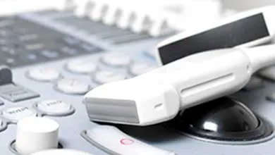 Close-up of a white ultrasound probe on an ultrasound machine's control panel.