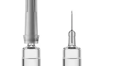 Two clear medical vials on a white background: one with a gray adapter, the other with an attached needle.
