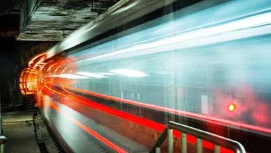 Long-exposure of a train in a dark tunnel, blurred into streaks of red and white light.