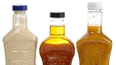 Close-up of three salad dressing bottles on a white background.