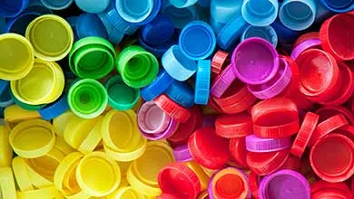 Brightly colored plastic bottle caps grouped together in red, blue, green, yellow, and purple.