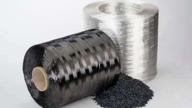 Black and silver spools of polymer fiber with a small pile of black plastic pellets in front.