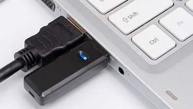 笔记本电脑的特写，多个电缆和适配器连接到其端口。