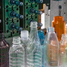 The plastic bottles and injection mold in background. PET plastic bottle manufacturing concept.